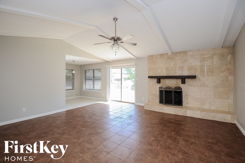 an empty living room with a fireplace and a ceiling fan