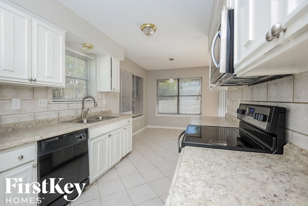 a kitchen with white cabinets and granite counter tops and black appliances
