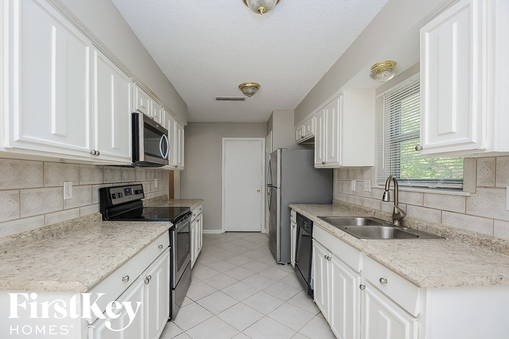 a kitchen with white cabinets and a sink and a refrigerator
