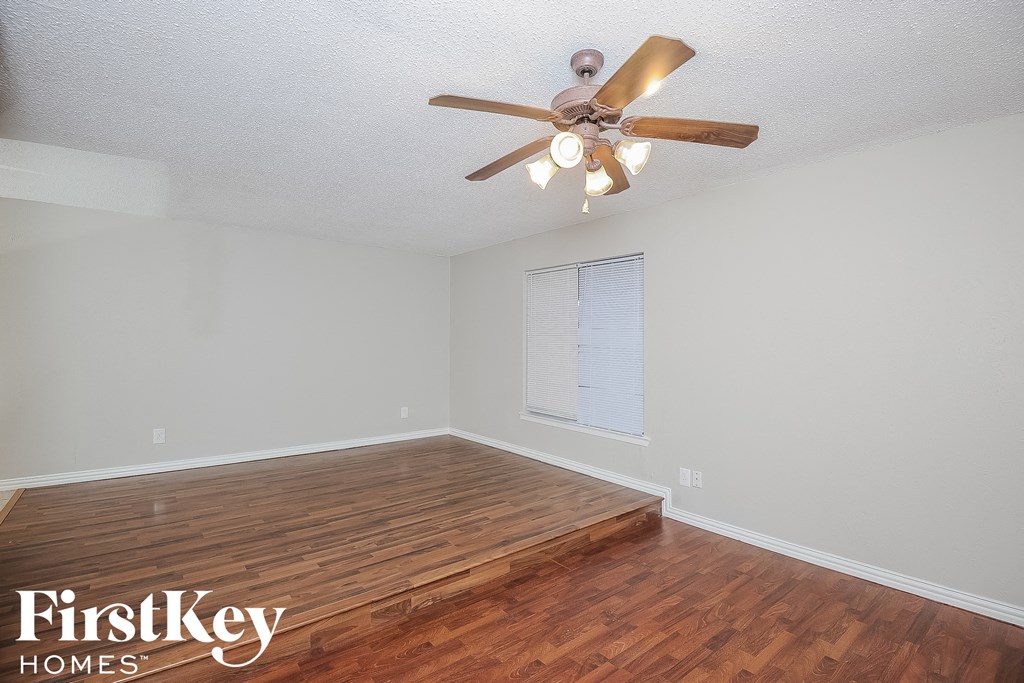a living room with wood floors and a ceiling fan