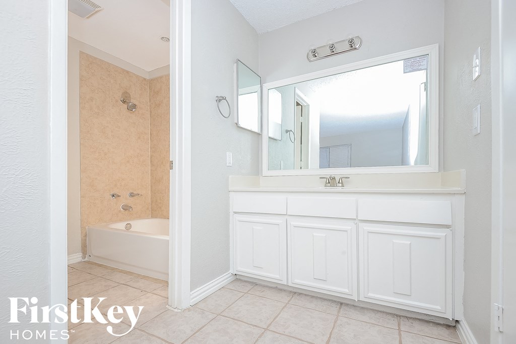 a white bathroom with a sink and a tub and a mirror