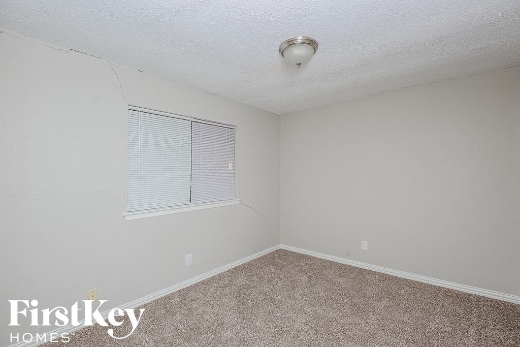 a bedroom with a window and a carpeted floor