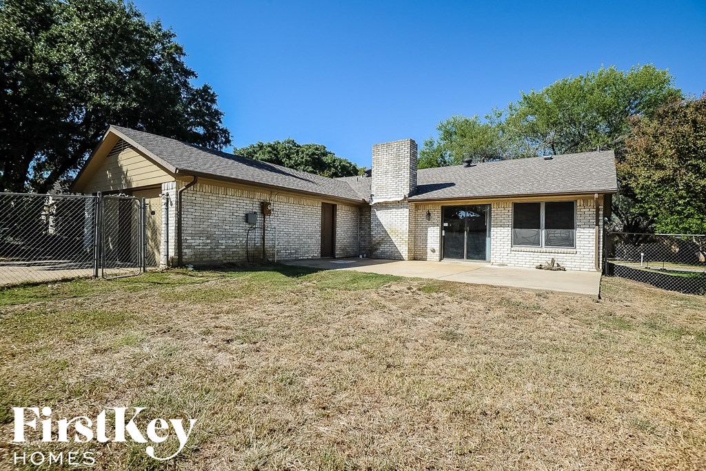 a white brick house with a yard and a fence