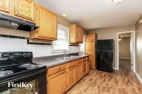A kitchen with wooden cabinets and a black refrigerator.