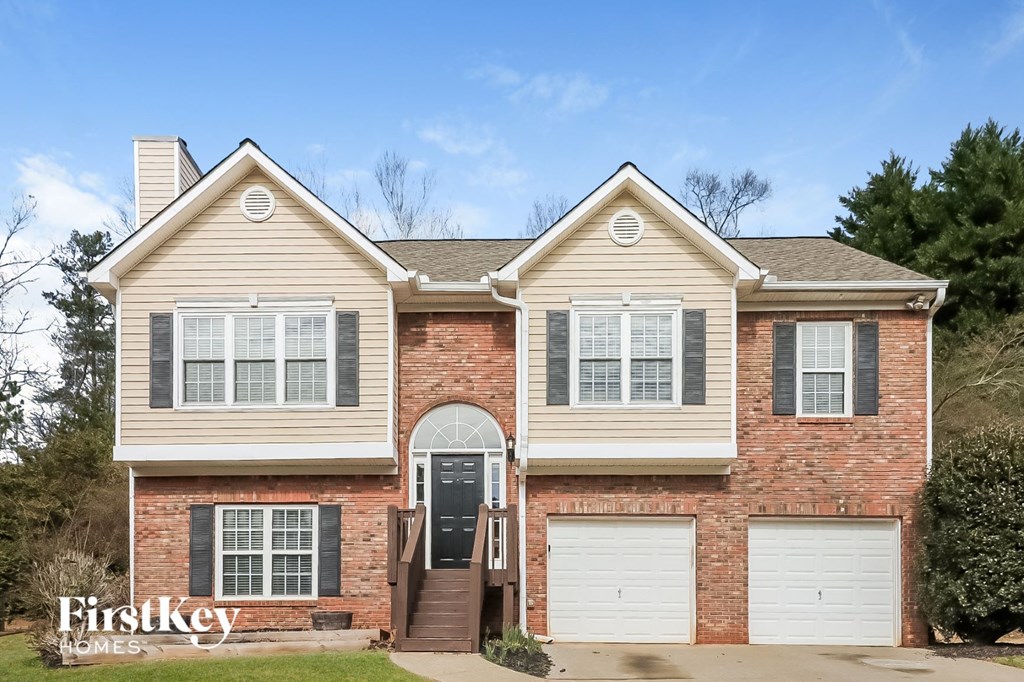 A two-story brick house with a black door and white garage doors.