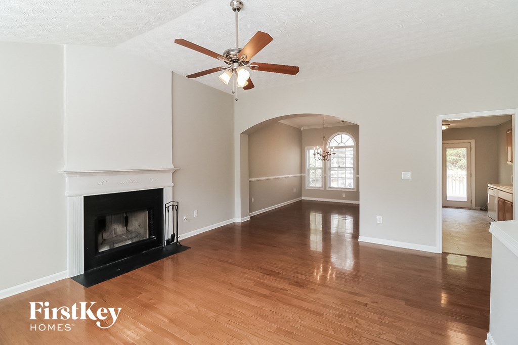 A spacious living room with a fireplace and a ceiling fan.