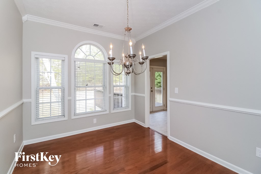 A well-lit room with a chandelier and wooden floors.