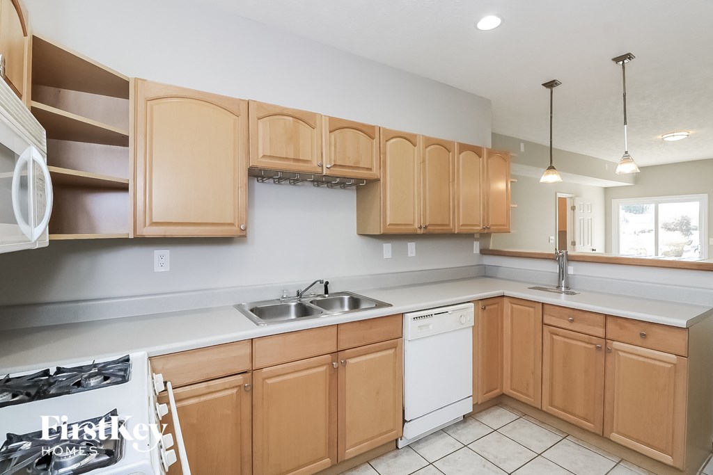 A kitchen with wooden cabinets and a white dishwasher.