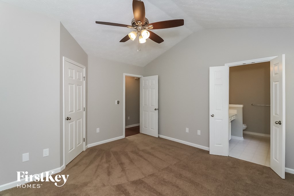 A room with a ceiling fan and carpeted floor.