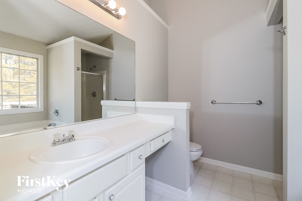A white bathroom with a sink, toilet, and a window.