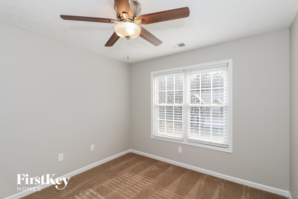A room with a ceiling fan and a window with blinds.