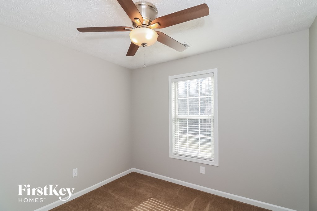 A room with a ceiling fan and a window with blinds.