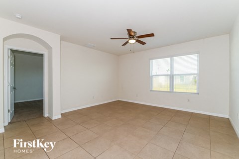 A spacious room with a ceiling fan and a window with blinds.