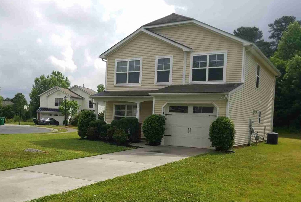 a yellow house with a driveway and a white garage door