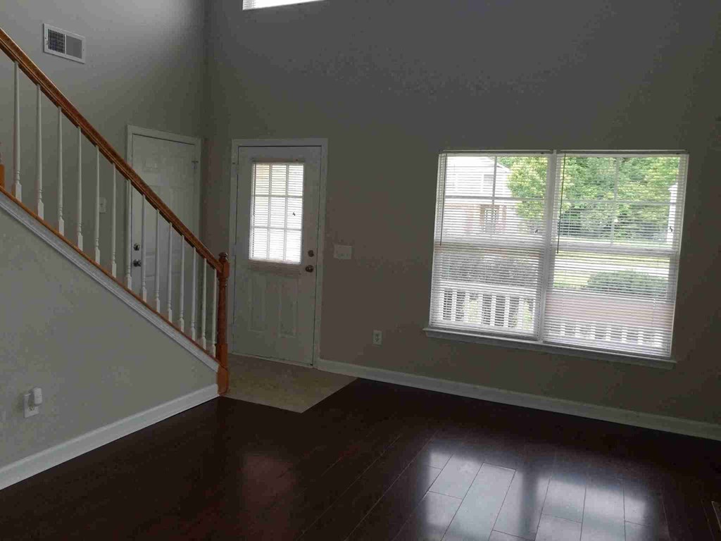 the living room of a house with a staircase and two windows