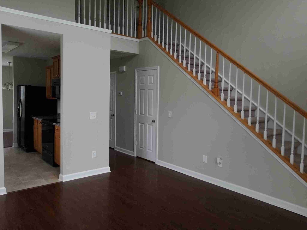 an empty living room with a staircase and a white door