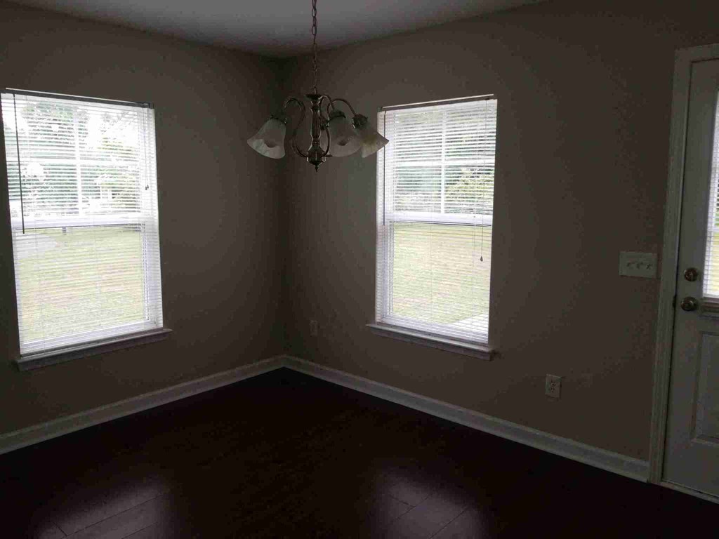 a dining room with two windows and a chandelier