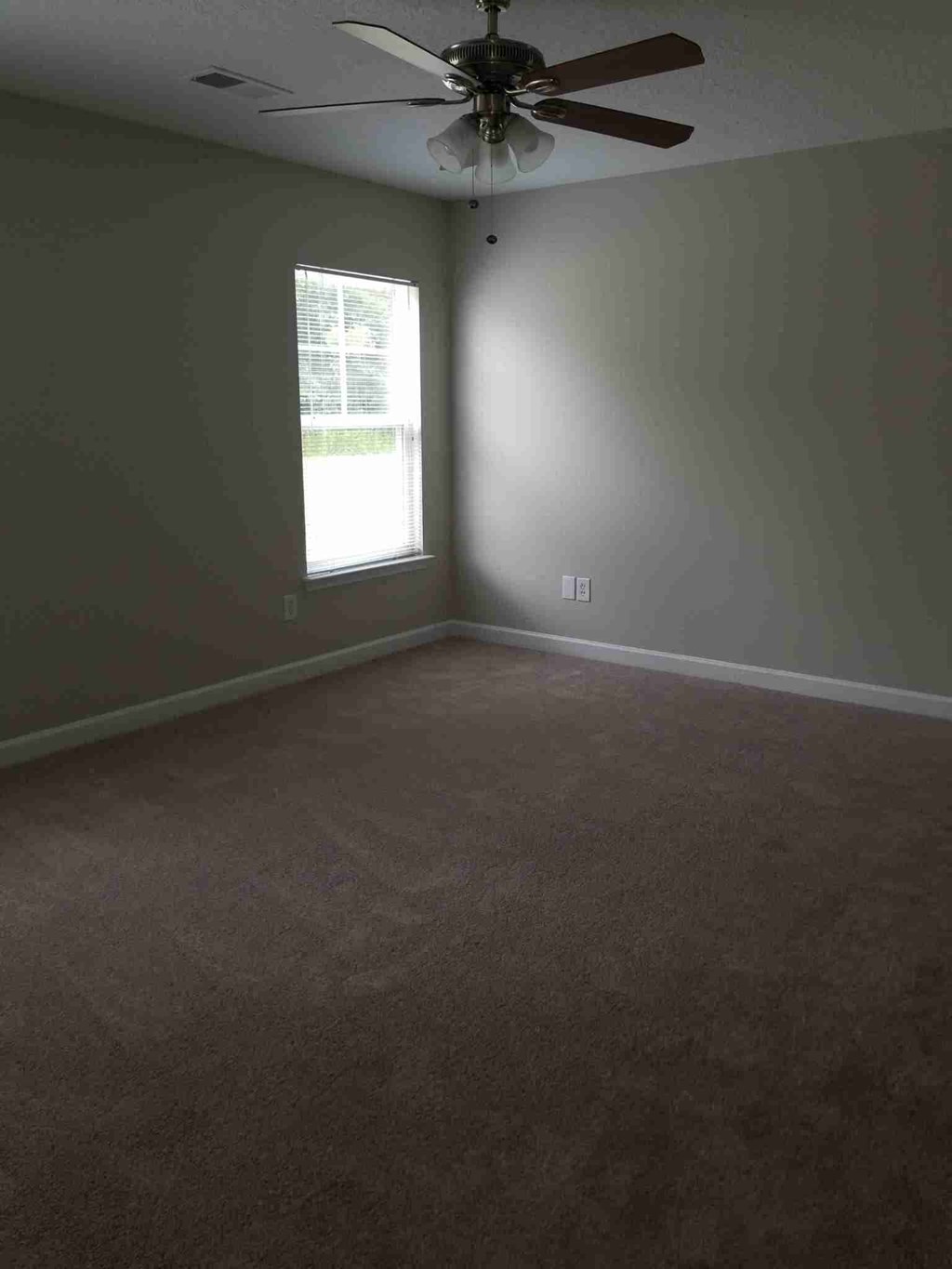 an empty room with a ceiling fan and a window