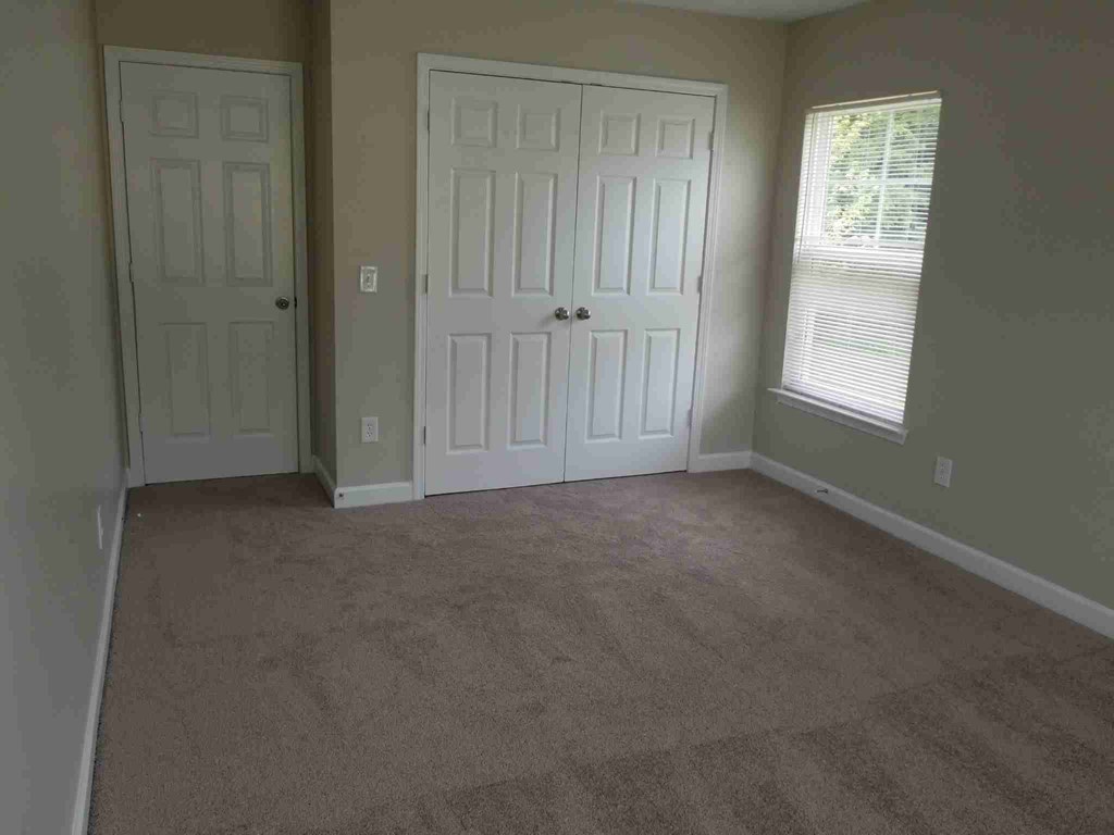 an empty room with a carpeted floor and two doors