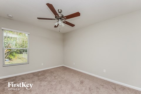 the master bedroom has a ceiling fan and a beige carpet