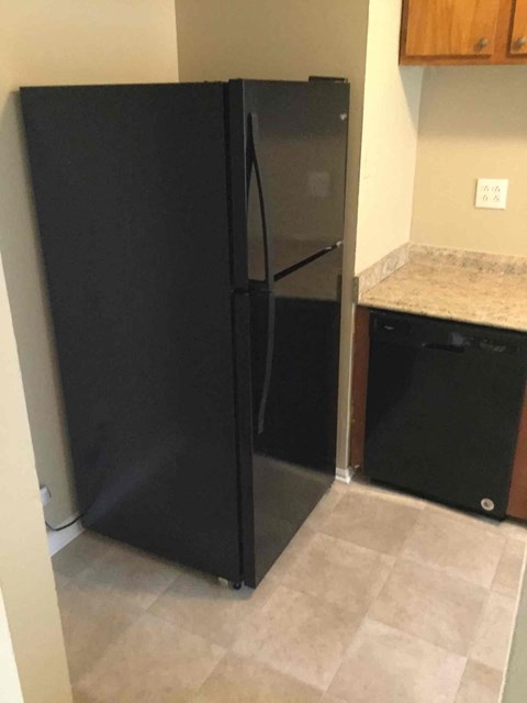 A black refrigerator in a kitchen with a black dishwasher.