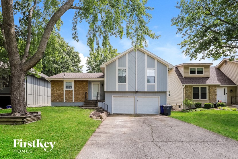 a white and tan house with a driveway and a tree