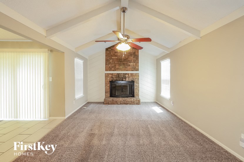 an empty living room with a fireplace and a ceiling fan