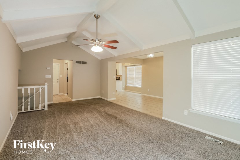 a large empty living room with a ceiling fan