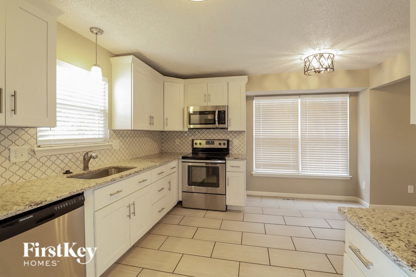 a kitchen with white cabinets and a sink and a stove