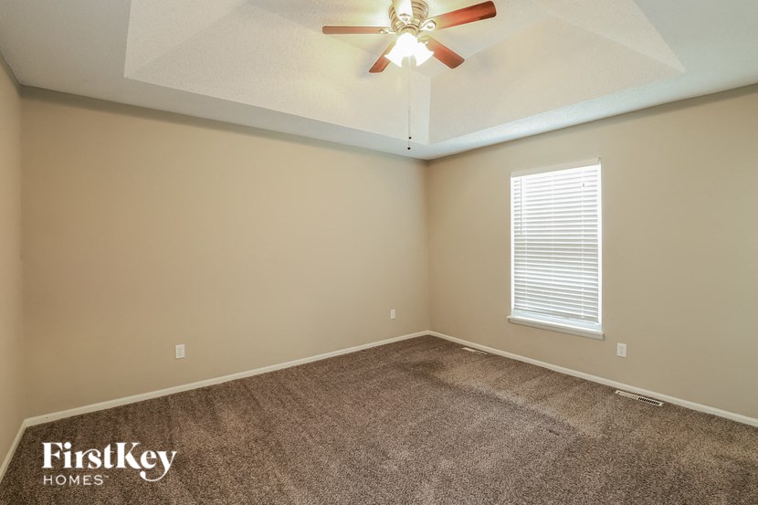 the living room of an empty home with a ceiling fan