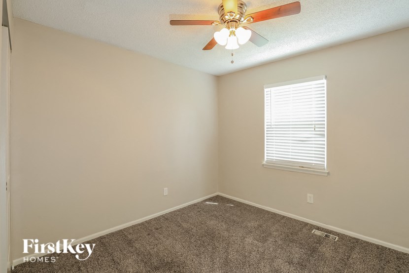 a bedroom with carpet and a ceiling fan and a window