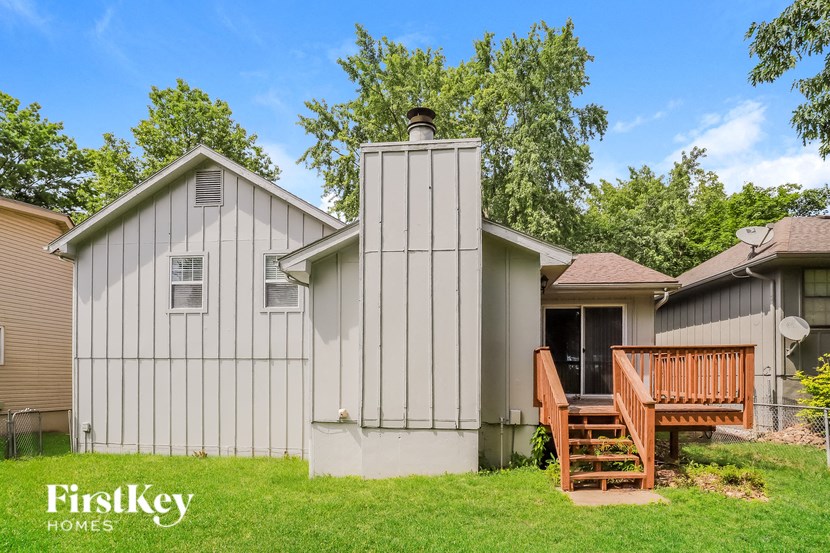 a small gray house with a wooden deck in front of it