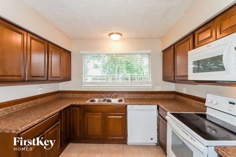 A kitchen with brown cabinets and a white dishwasher.