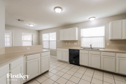 A kitchen with white cabinets and a black dishwasher.