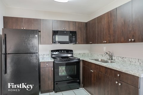 A kitchen with a black fridge and stove top oven.
