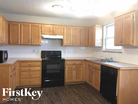 A kitchen with wooden cabinets and black appliances.
