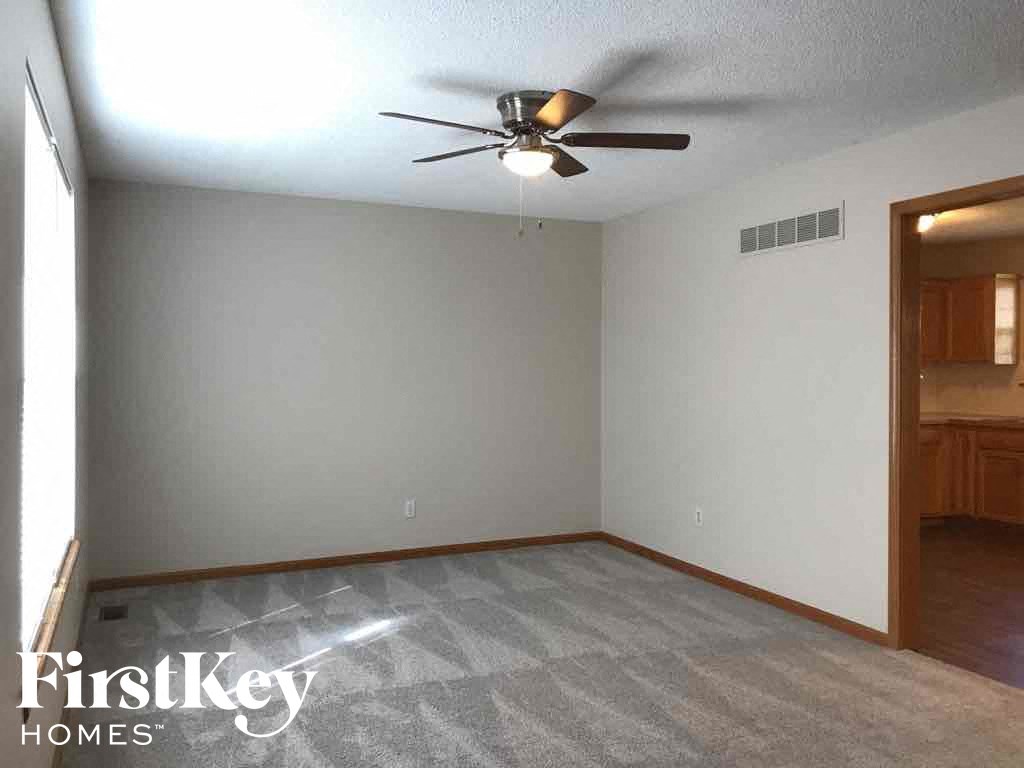 A room with a ceiling fan and a carpeted floor.