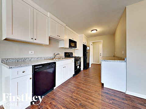 a kitchen with white cabinets and black appliances and a wood floor