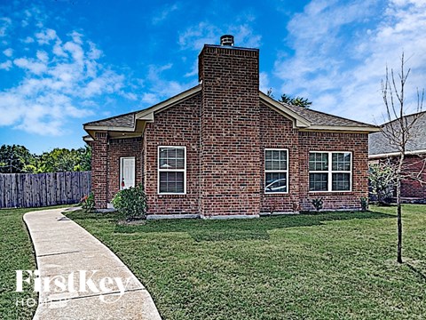 A brick house with a white door and windows is for sale.
