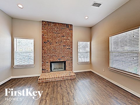 A room with a brick fireplace and wooden floors.