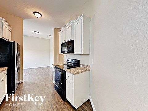 A kitchen with white cabinets and a black fridge.
