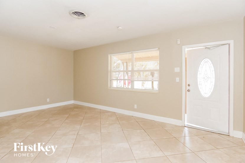 an empty living room with a white door and tiled floor