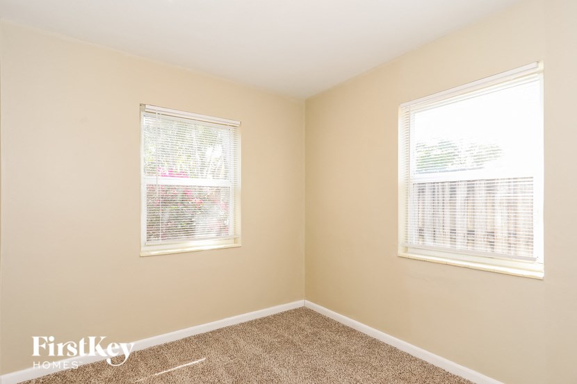 a bedroom with two windows and a carpeted floor