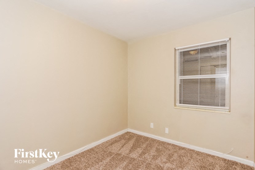 a bedroom with a window and a carpeted floor