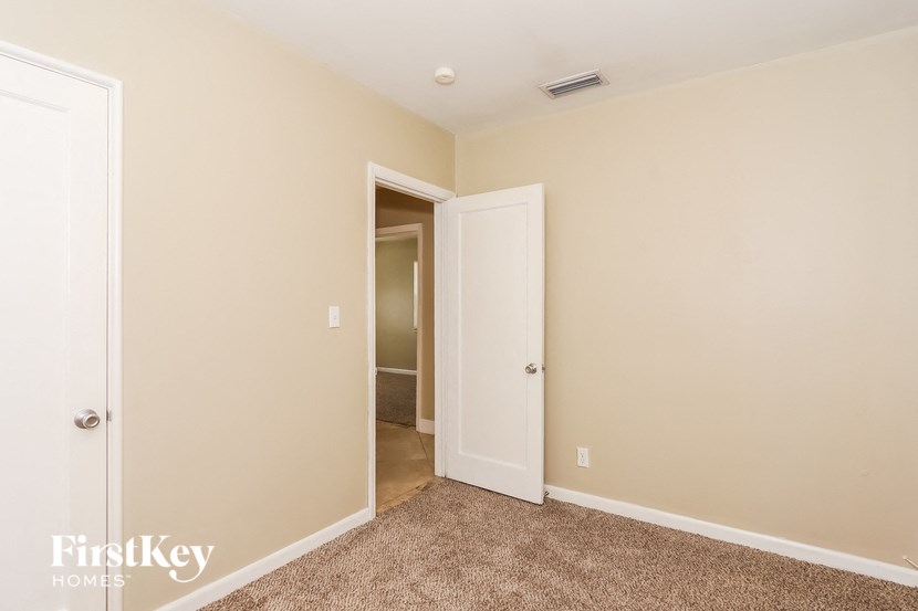 a bedroom with a door to a hallway and a carpeted floor