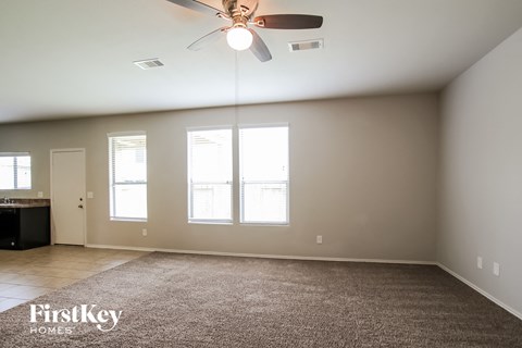 A spacious room with a ceiling fan and large windows.