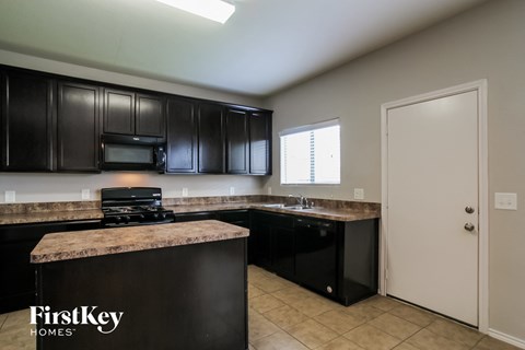 A kitchen with black cabinets and a countertop with a microwave on it.