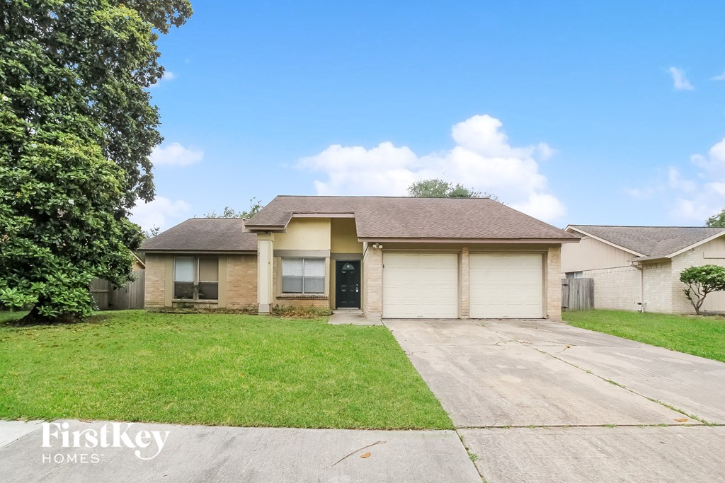 a yellow house with a lawn and a driveway
