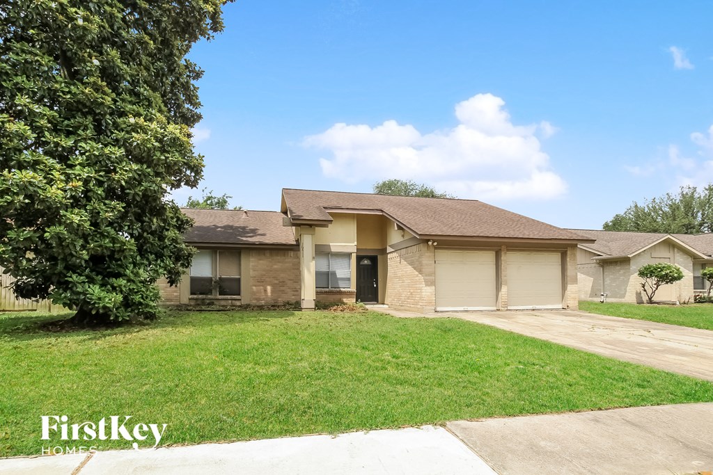a tan brick house with a yard and a tree