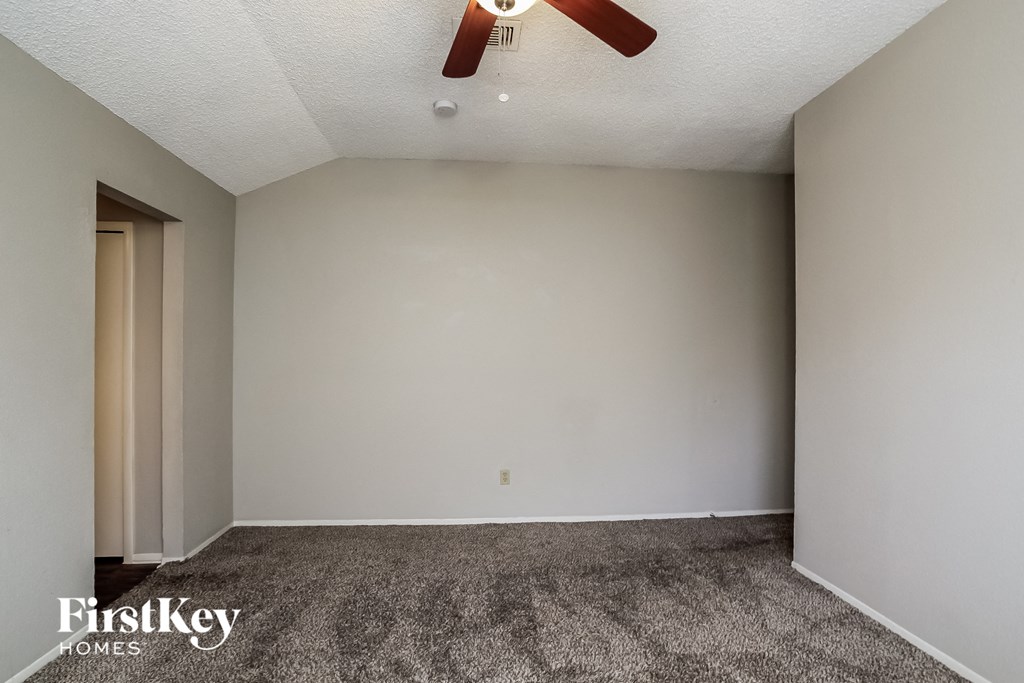 a empty living room with carpet and a ceiling fan